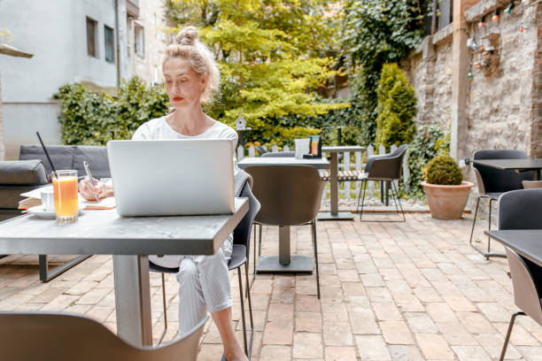 istock Smiling senior woman sitting in coffee shop using laptop. 1328501909
