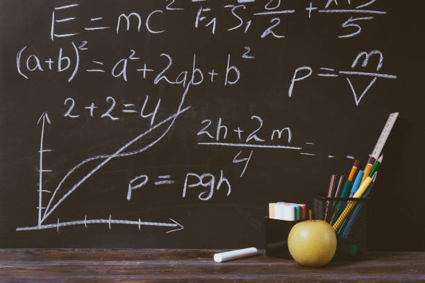 istock formulas, chalk inscriptions on a  blackboard, pens,  apples, markers, on the table, 1328504671