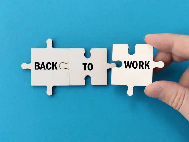 Photo of Back To Work Concept, hand assembling the pieces of the puzzle