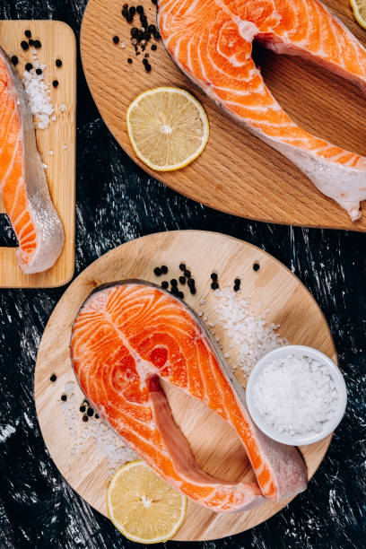 istock Salmon fish steak on a black background, top view. Vertical photo 1328508850