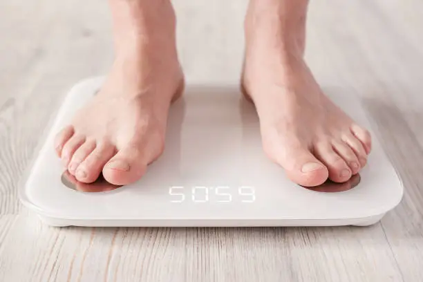 Bare feet stand on smart scales that makes bioelectric impedance analysis, BIA, body fat measurement. Concept of the Internet of things. Close-up..