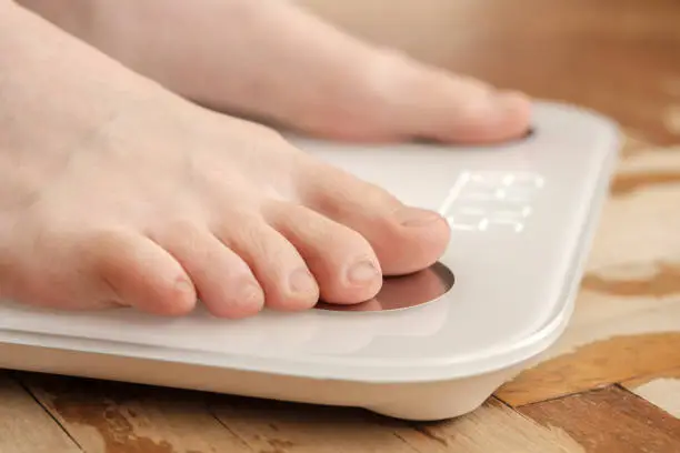 Female bare feet stand on smart scales that makes bioelectric impedance analysis, BIA, body fat measurement. Concept of the Internet of things. Close-up..