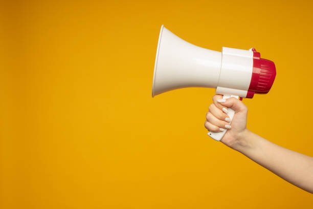 frau mit megaphon auf gelbem hintergrund - megaphone women at attention using voice stock-fotos und bilder