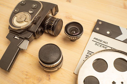 Movie clapper, film reel and camera on wooden background, top view