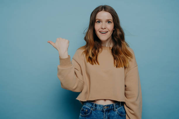 istock Excited young girl pointing finger somewhere posing over blue background 1328513005