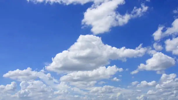 White clouds of various sizes in the bright blue sky.