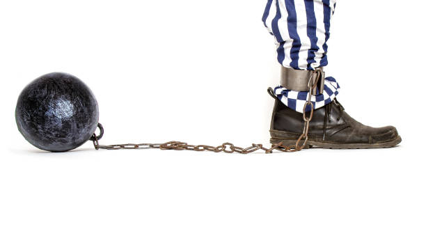 una gamba di un prigioniero in pantaloni a righe e uno stivale ruvido incatenato con una palla di ferro con catene di profilo - debt trapped chain ball and chain foto e immagini stock