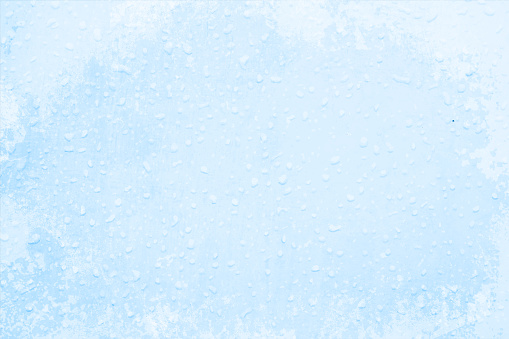 A blue coloured grunge background with frost drops all over having textured look as that of rain drops sticking to a wall.