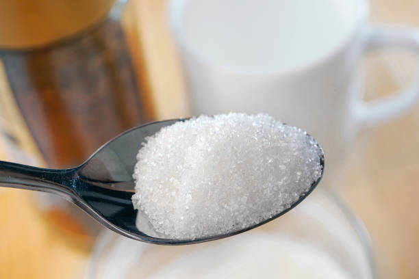 설탕 숟가락의 클로즈업. 흰 컵과 커피 항아리의 배경에 과립 설탕의 숟가락. 건강에 해로운 식습관 - risk factors condition diabetes 뉴스 사진 이미지