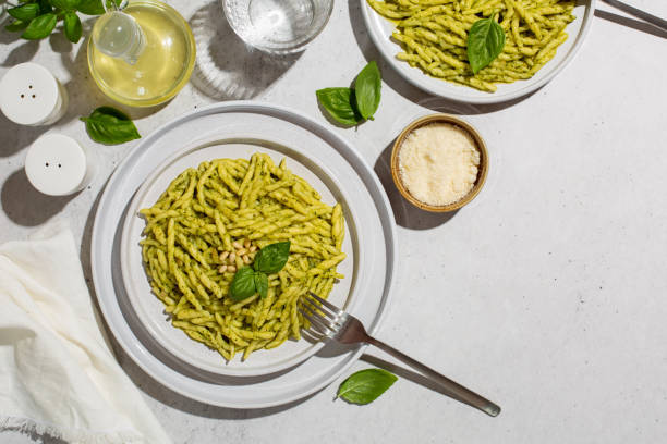 итальянский обед. trofie al pesto, паста с соусом песто из листьев базилика, твердого сыра, кедровых орехов, чеснока, оливкового масла.  жесткий све� - pesto sauce italian culture pine nut photography стоковые фото и изображения