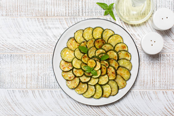 istock Roasted young zucchini on white wooden table. Top view, copy space. 1328518693