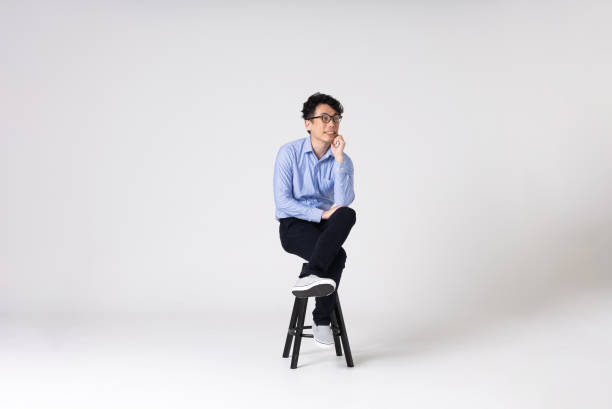 Full-length portrait of an Asian man on a white background. Full-length portrait of an Asian man on a white background.
Full body shot. Japanese male, 30s.
Healthy and confident figure.
sitting on a chair. legs crossed at knee stock pictures, royalty-free photos & images