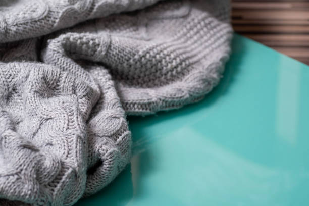 istock Fragment of knitted gray fabric on a glossy turquoise background. 1328519653
