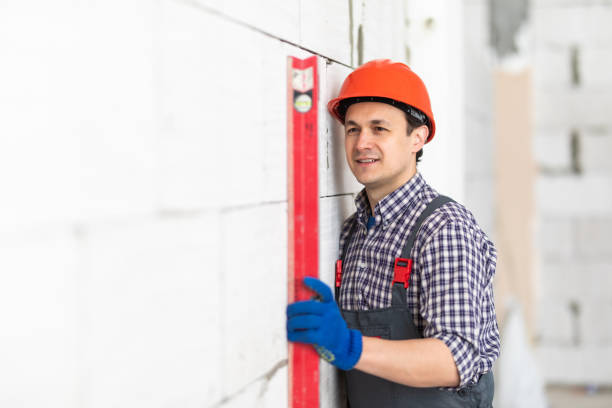 istock Worker using water level meter measuring the wall builder working with autoclaved aerated concrete blocks. Walling, installing bricks in construction site. 1328524279