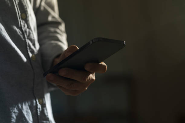 istock Close-up of man using mobile phone on dark background. 1328525592
