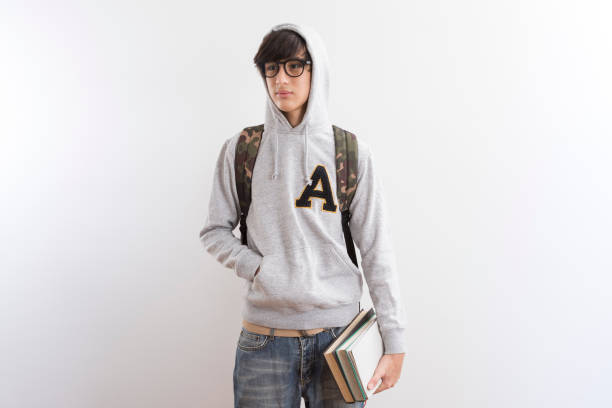 Handsome teen boy students carrying a backpack and books standing on white background.