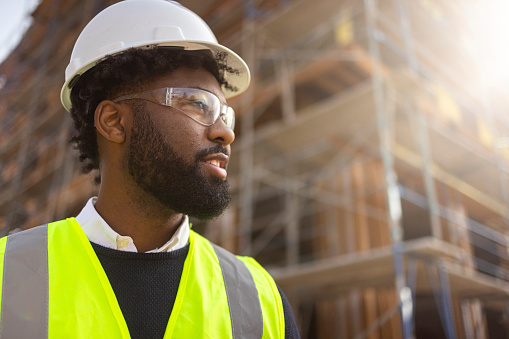 A young black man is a project manager at a residential construction site.