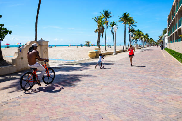 paseo marítimo de la playa en florida con personas sinceras montando en bicicleta corriendo trotando - beach family boardwalk footpath fotografías e imágenes de stock