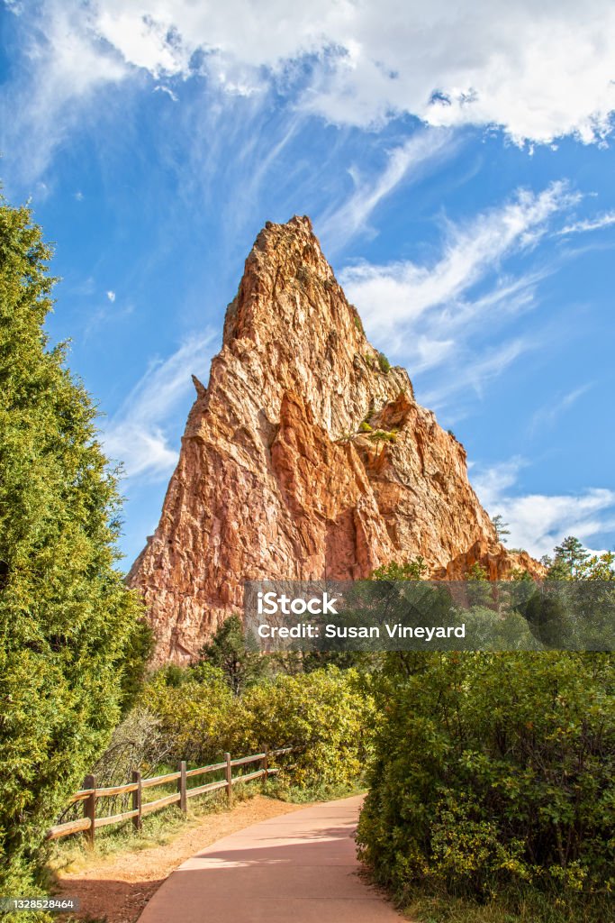 Walking path with rustic fence through trees and past jutting red stone outcropping at Garden of the Gods in Colorado Springs Colorado USA Springtime Stock Photo