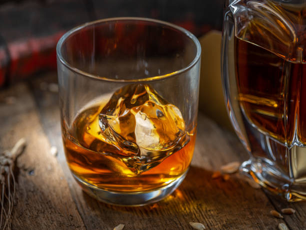 garrafa de whisky y vaso de whisky sobre viejo barril de madera en el fondo oscuro. - gin decanter whisky bottle fotografías e imágenes de stock