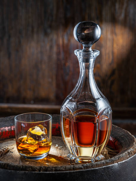 暗い背景にある古い木製の樽の上にウイスキーとウイスキーのガラスのキャラフェ。 - gin decanter whisky bottle ストックフォトと画像