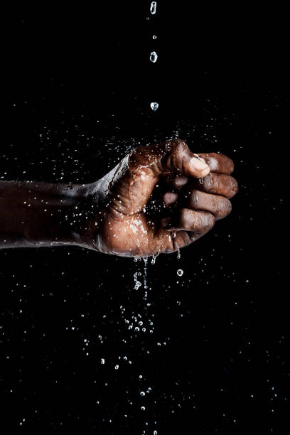 istock African man hand interacting with water and black background. 1328530802