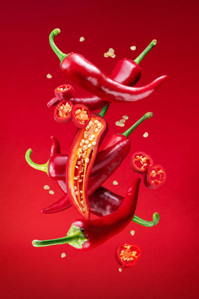 Fresh red chilli peppers and cross sections of chilli pepper with seeds floating in the air. File contains clipping paths. stock photo