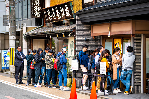 Kyoto, Japan - April 17, 2019: Many people crowded locals standing at Teramachi Fukuda restaurant near Nishiki market for traditional kaiseki food cuisine