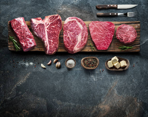 istock Different raw beef steaks on the wooden board on the grey table. Top view. 1328532193