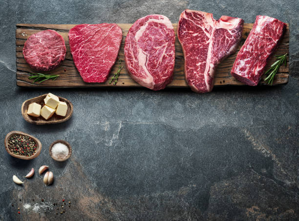 istock Different raw beef steaks on the wooden board on the grey table. Top view. 1328532201