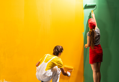 Young couple painting wall in  their room