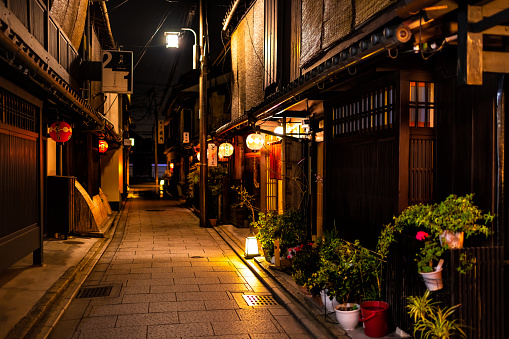 Kyoto, Japan - April 16, 2019: Narrow empty alley street in Gion district at dark evening night with illuminated red lanterns paper lamps at entrance to izakaya restaurant and nobody