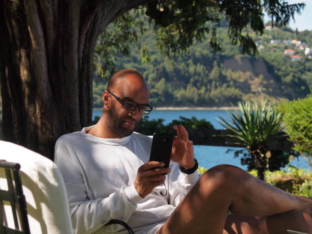 istock Man working  on vacation by the sea, using his laptop and smartphone 1328536102