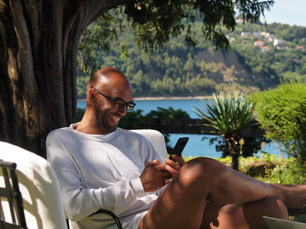 istock Man working  on vacation by the sea, using his laptop and smartphone 1328536124