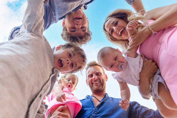 shot from below of a young adult family time having fun outdoors. mom and dad portrait carrying kids on holiday with children. cropped low view of happy people. joy, togetherness and lifestyle concept - directly below fotos imagens e fotografias de stock