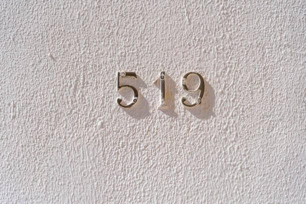 Metal house number 519 on a white stucco wall background