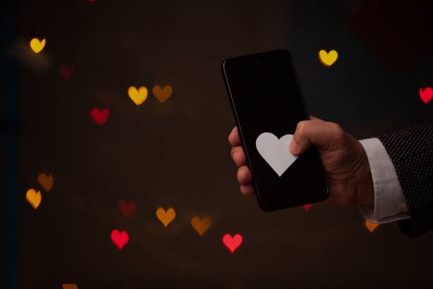 istock Man hand holds phone and paper heart 1328542892