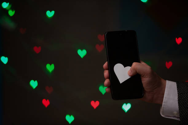 istock Man hand holds phone and paper heart 1328542903