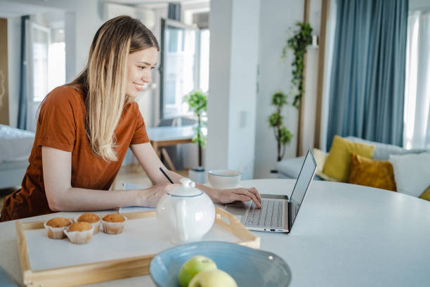istock Young woman is eating breakfast and using laptop 1328543277