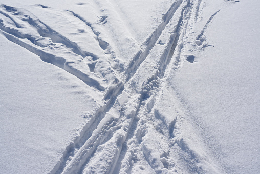 Ski tracks on white snow, top view.