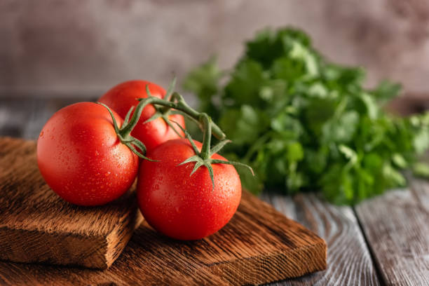 Fresh ripe tomatoes on a vintage cutting board, dark old wooden table. Selective focus. Side view. Fresh ripe tomatoes on a vintage cutting board, dark old wooden table. Selective focus. Side view vine tomatoes stock pictures, royalty-free photos & images