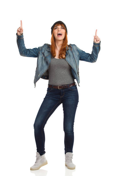 istock Young Woman In Jeans Jacket And Cap Is Standing, Pointing Up And Shouting 1328548052