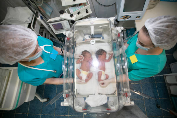 a children's doctor stands with a box for newborns in a children's hospital. - eeneiige tweeling stockfoto's en -beelden
