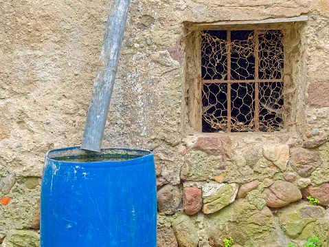 Dilapidated rustic window and brilliant blue rain barrel found in the countryside region of Trentino-South Tyrol and the Dolomites in Italy