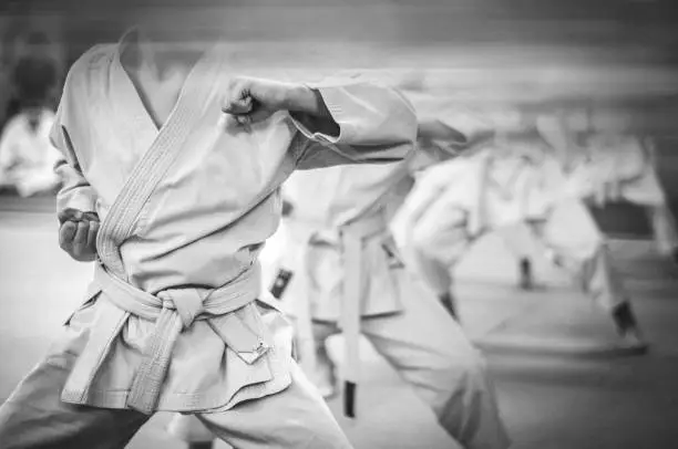 Elbow punch in karate. Children's training. Black and white photo with film grain effect.
