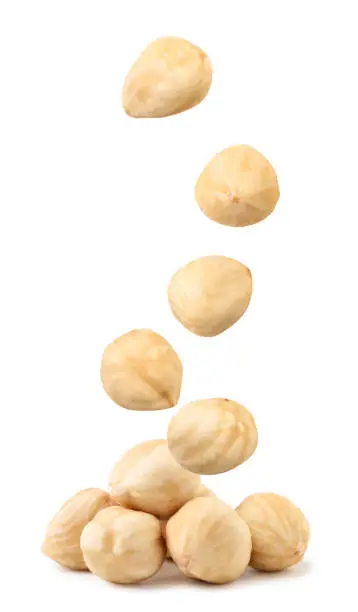 Peeled hazelnuts fall on a heap close-up on a white background. Isolated