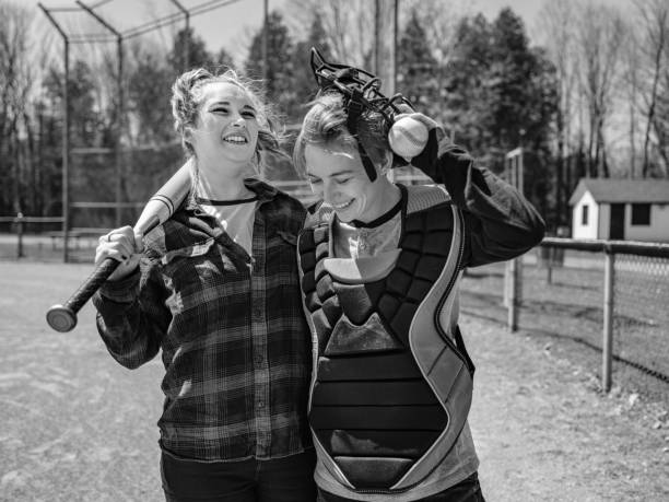 Female LGBTQ couple playing baseball outdoor Female LGBTQ couple practising baseball at the baseball field. Young transgender woman and young lesbian woman dressed in casual clothes with baseball gear. Exterior of public baseball field in the park. transgender-athletes stock pictures, royalty-free photos & images