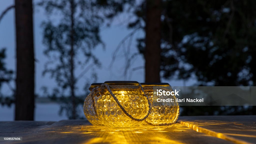 Portable garden lights on a wooden table outdoors in Finnish summer twilight Close-up picture of solar powered garden lights in Finnish twilight Garden Stock Photo