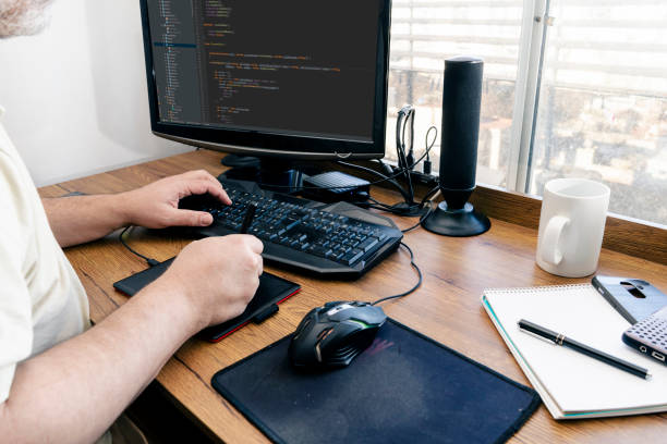 istock View of a man's hands from behind holding a pen and typing at the same time while working with a graphic tablet at his desk. Concept design and teleworking, homeworking. 1328559753