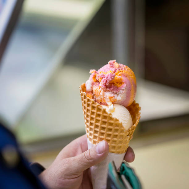 istock Fruit ice cream mix in waffle cone in female hand. Selective focus. Real scene 1328562261